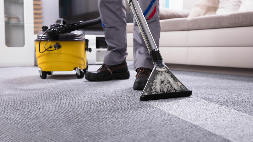 Man vacuuming a carpet in a business.